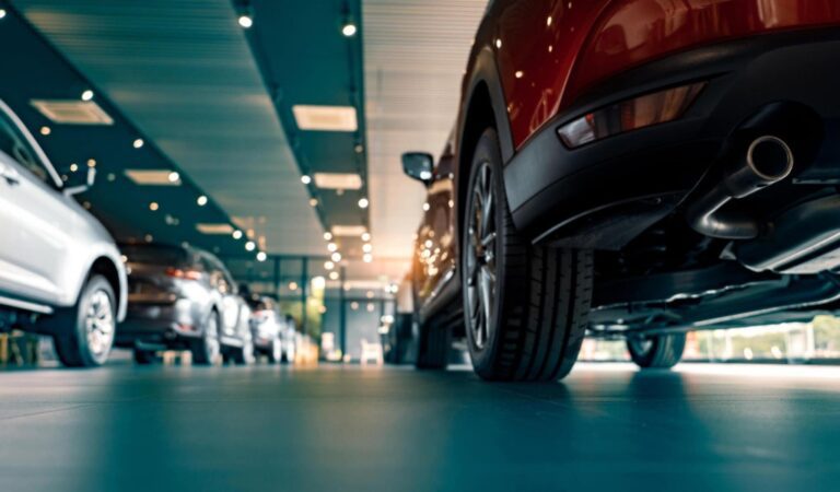 Sleek cars lined up in a modern car rental showroom with clear view of the polished floor reflecting the vehicles..